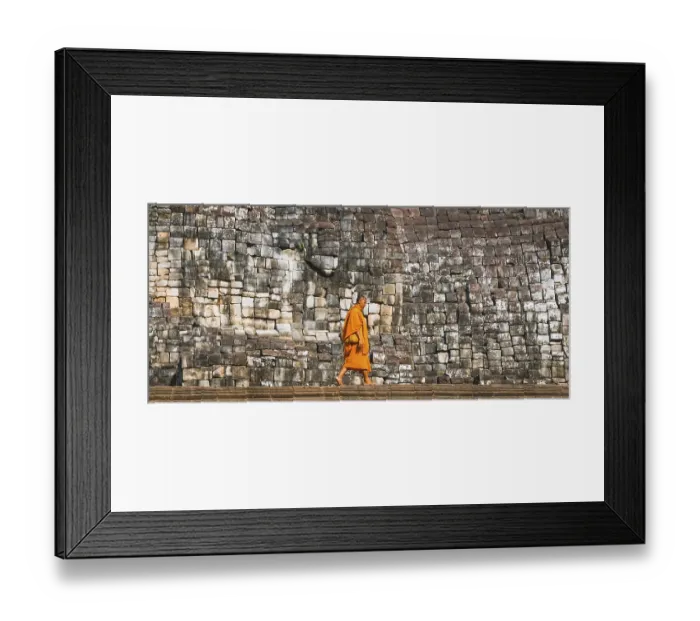 Framed Print : Buddhist monk walks in front of old stone wall Framed Print : Buddhist monk walks in front of old stone wall