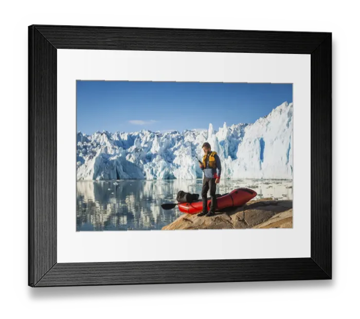 Framed Print : Man with packraft on fjord, satellite phone in hand