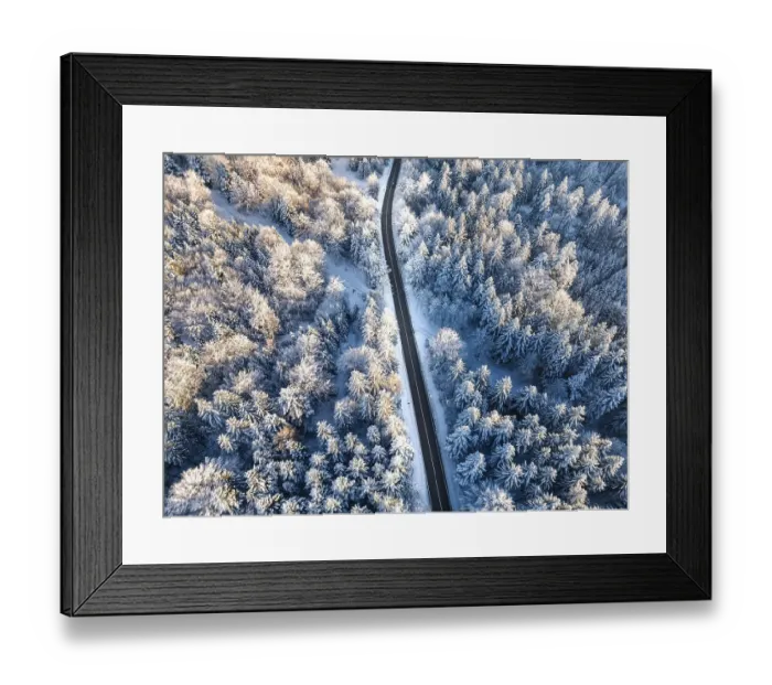 Framed Print : Aerial view of a snowy, winding road through a coniferous forest in winter Framed Print : Aerial view of a snowy, winding road through a coniferous forest in winter