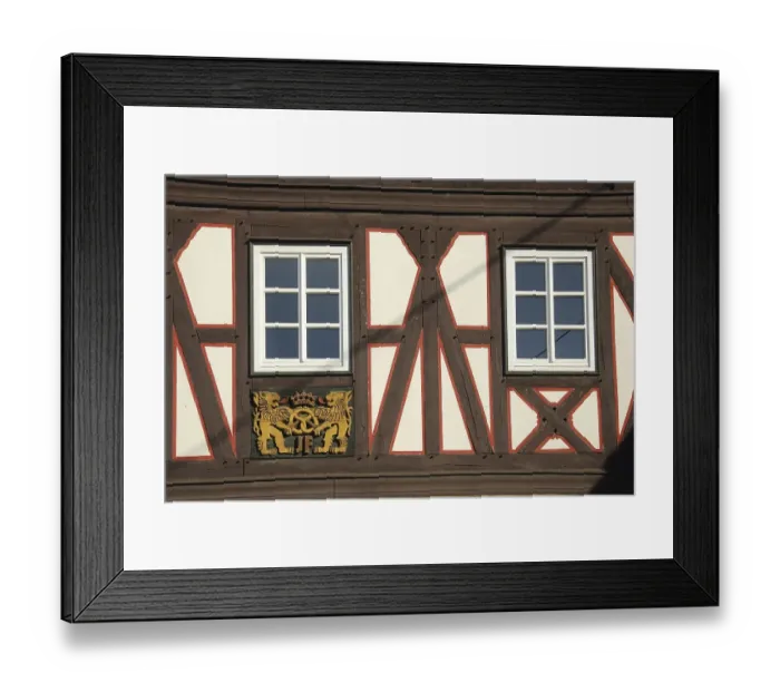 Framed Print : Wood carving with lion figures and pretzel on half-timbered house