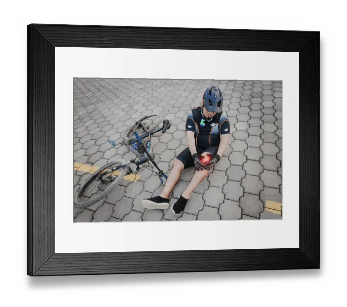 Framed Print : Unhappy cyclist sitting on the pavement with knee pain Framed Print : Unhappy cyclist sitting on the pavement with knee pain