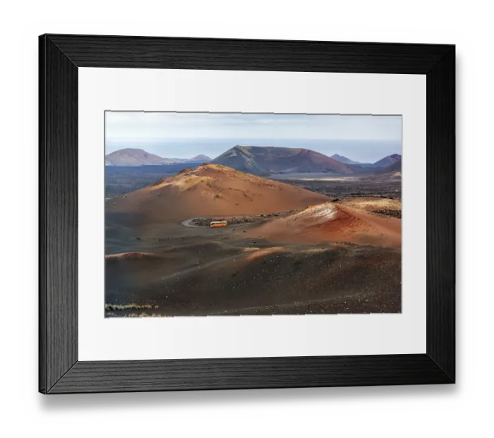 Framed Print : Orange-coloured coach with tourists drives through the fire mountains of Timanfaya National Park