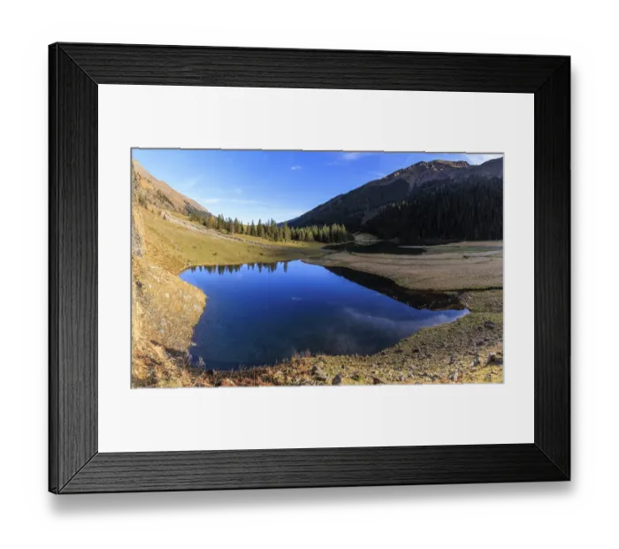 Framed Print : A clear lake surrounded by mountains and forests
