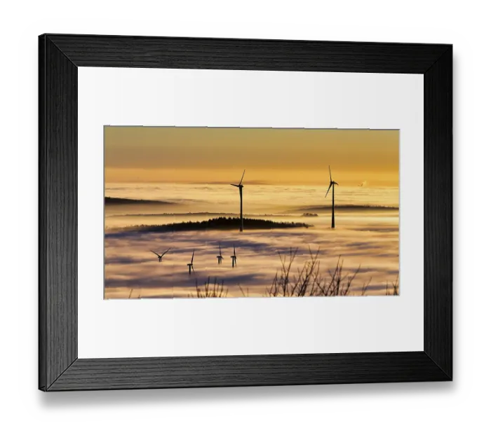 Framed Print : Wind turbines and forest rising from cloud cover