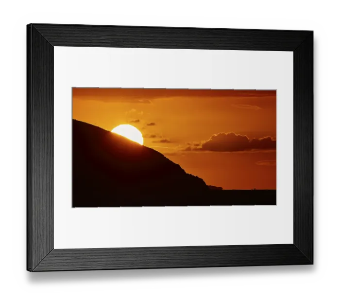 Framed Print : Sun setting behind a mountain, clear silhouette in front of an intense orange sky Framed Print : Sun setting behind a mountain, clear silhouette in front of an intense orange sky