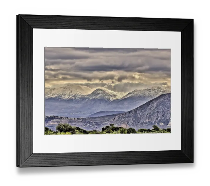 Framed Print : Snowy mountains under threatening grey clouds in a vast landscape with a dramatic atmosphere Framed Print : Snowy mountains under threatening grey clouds in a vast landscape with a dramatic atmosphere