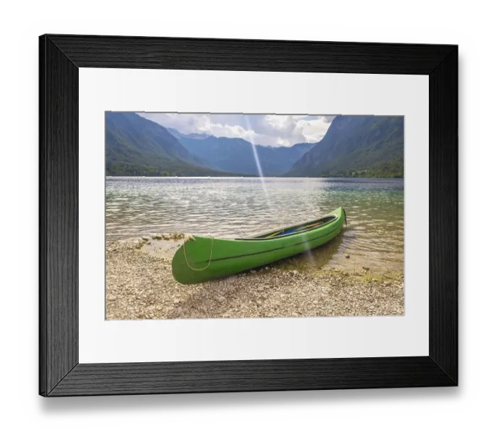Framed Print : Green canoe resting on the pebbled shore of lake bohinj