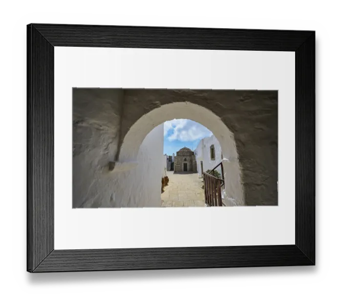 Framed Print : Passage through a stone arch with a view of white buildings and blue sky in the Greek monastery