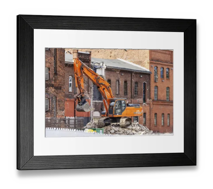 Framed Print : Demolition excavator in front of historic brick buildings
