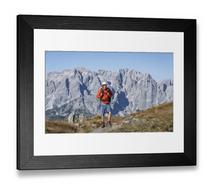 Framed Print : Mountaineer on hiking trail in front of rocky mountain peaks