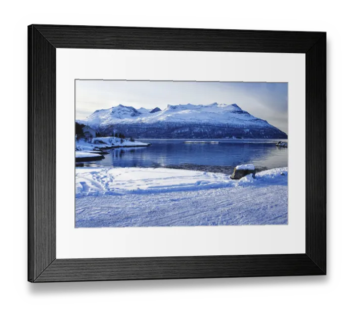 Framed Print : Snowy coastal landscape with mountains by the water