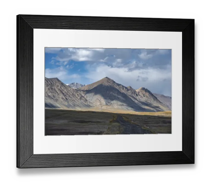 Framed Print : Gravel track on plateau, dramatic high mountains