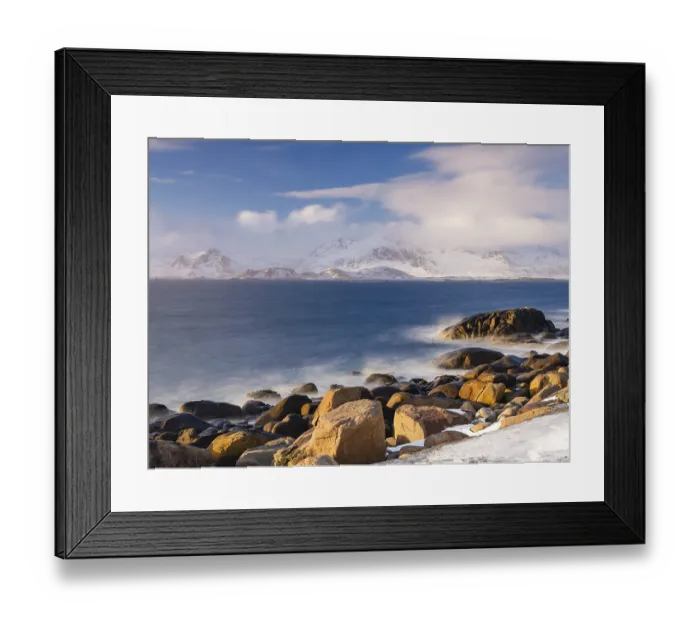 Framed Print : Rocky coast, snow-capped mountains in the background