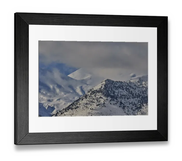 Framed Print : Snow-covered mountain range under a cloudy sky