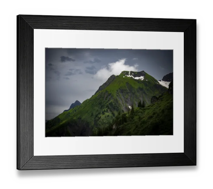 Framed Print : Grassy summit with remnants of snow and dramatic clouds