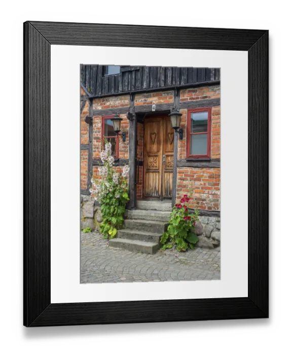 Framed Print : Hollyhocks (Alcea rosea) at a door tin a half-timbered house in a small street in the idyllic downtown of Ystad Framed Print : Hollyhocks (Alcea rosea) at a door tin a half-timbered house in a small street in the idyllic downtown of Ystad