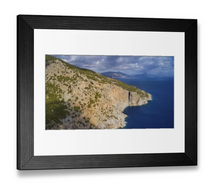 Framed Print : Drone shot, rocky coast with vegetation and view of the sea and the mountains in the background