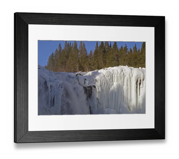 Framed Print : Snow-covered trees surround a frozen waterfall with impressive ice structures