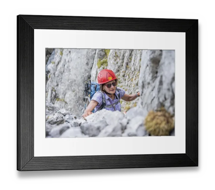 Framed Print : Female mountaineer with helmet climbing a rock face Framed Print : Female mountaineer with helmet climbing a rock face