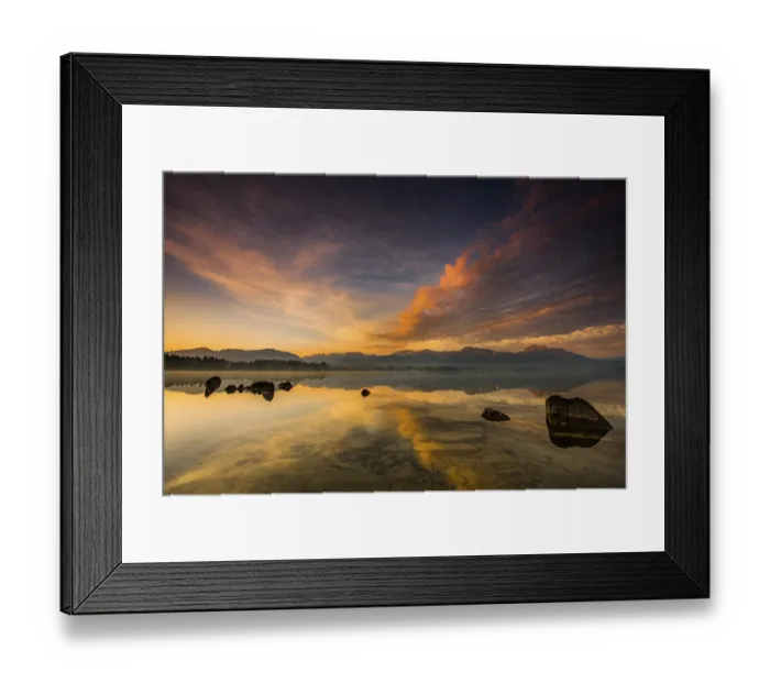 Framed Print : Forggensee with reflection of the cloudy sky and the Allgaeuer mountains in the background at sunrise