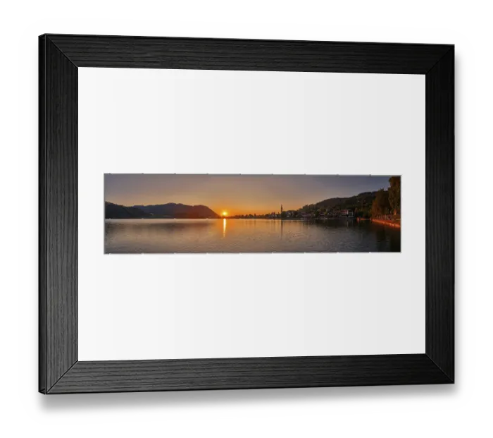 Framed Print : A peaceful sunset over a lake with mountains and a village in the background Framed Print : A peaceful sunset over a lake with mountains and a village in the background