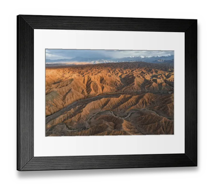 Framed Print : River bed runs through a landscape of eroded hills