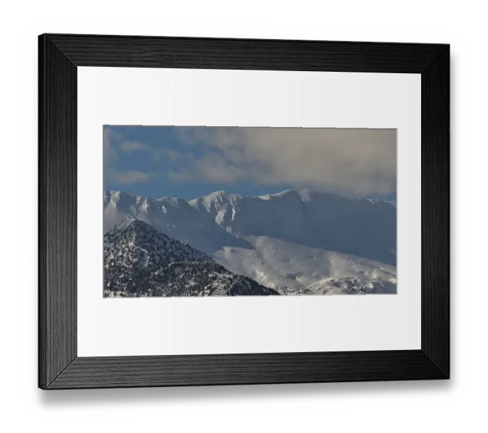 Framed Print : Snow-covered mountain peaks under a clear blue sky with scattered clouds