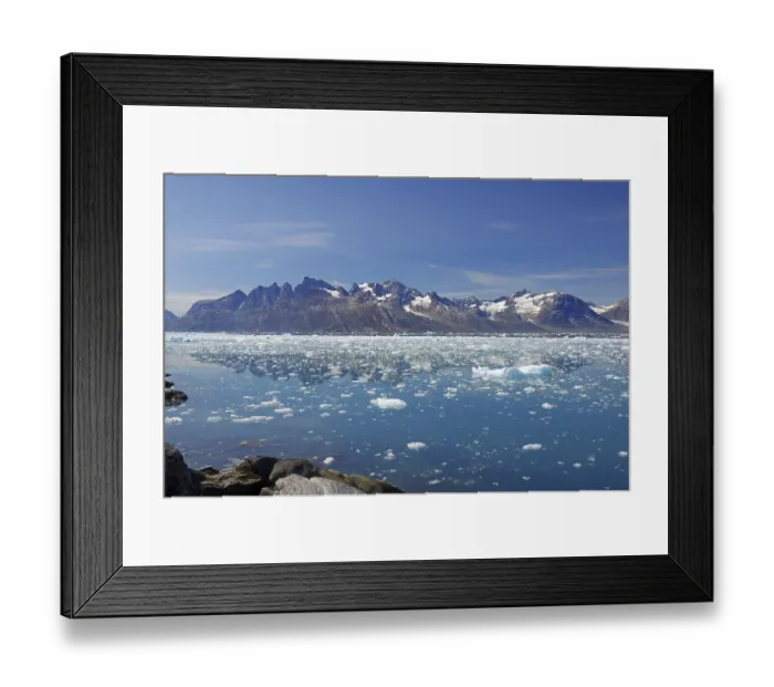 Framed Print : Icebergs floating in crystal clear water with mountains in the background under a blue sky