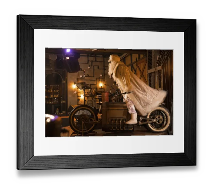 Framed Print : Side view of brutal Santa Claus in white clothes standing on vintage motorbike in grunge rock bar