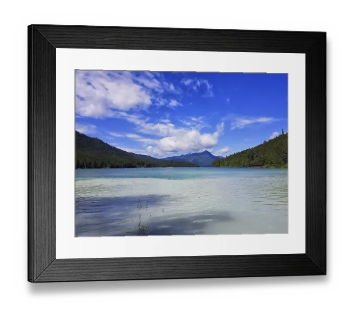 Framed Print : A clear lake with surrounding mountains and wooded slopes under a blue sky with white clouds Framed Print : A clear lake with surrounding mountains and wooded slopes under a blue sky with white clouds