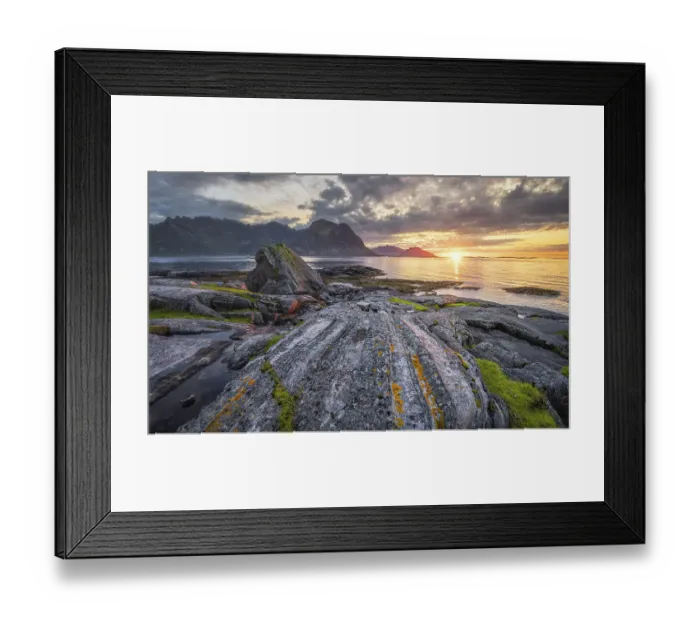 Framed Print : Sunset at the sea, in front rocky coast with grass and lichens