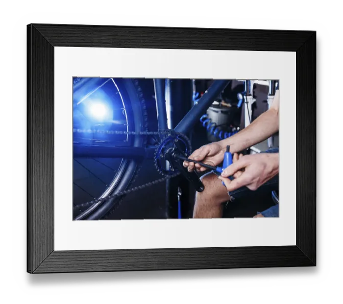 Framed Print : A close-up of a male bicycle mechanic's hand in the workshop uses a screwdriver tool to adjust Framed Print : A close-up of a male bicycle mechanic's hand in the workshop uses a screwdriver tool to adjust