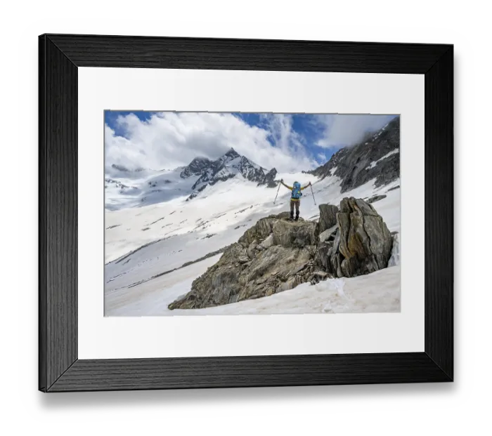Framed Print : Mountaineer on a rock between snow