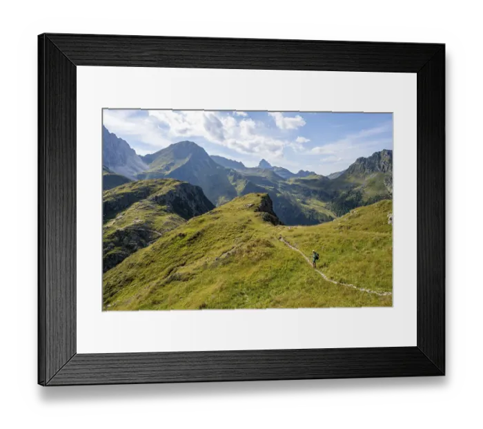 Framed Print : Mountaineer on a hiking trail on a grassy mountain ridge