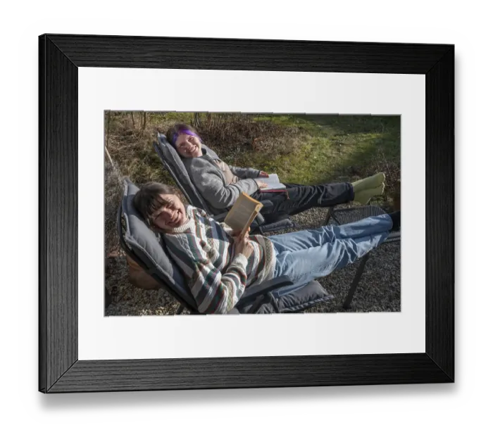 Framed Print : Two young woman in a deckchair reading in the garden