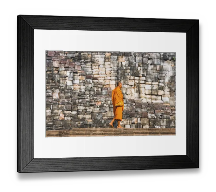 Framed Print : Buddhist monk walks in front of old stone wall