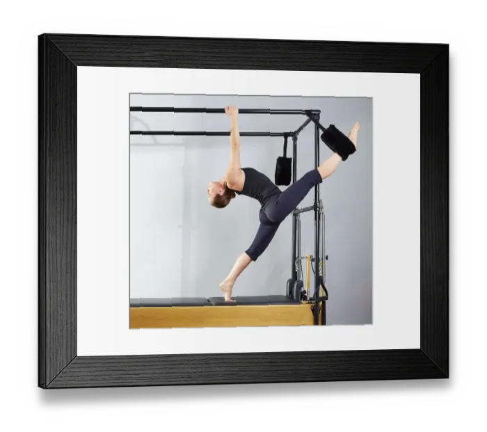 Framed Print : Pilates woman in cadillac split legs stretch exercise at gym