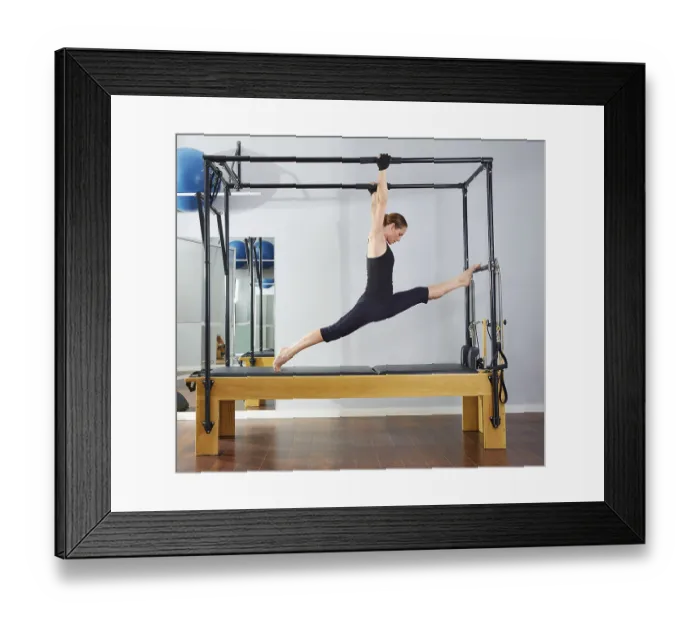 Framed Print : Pilates woman in cadillac legs split reformer exercise at gym