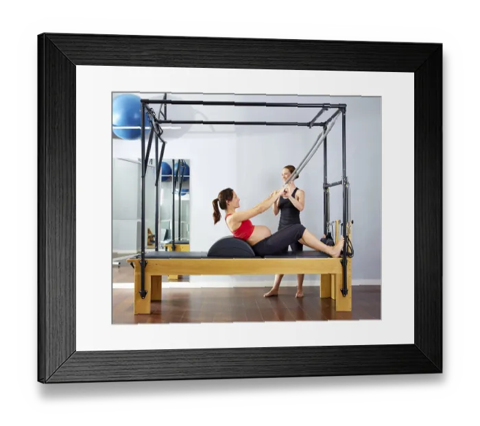 Framed Print : Pregnant woman pilates reformer roll up cadillac exercise with personal trainer