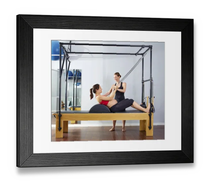 Framed Print : Pregnant woman pilates reformer roll up cadillac exercise with personal trainer