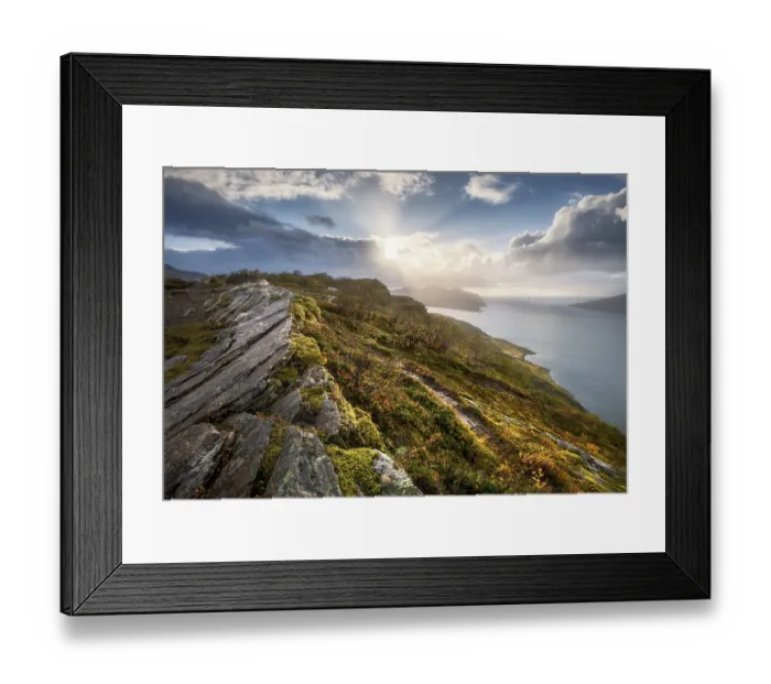 Framed Print : Sun breaks through dramatic clouds on the fjord with rocks and coloured moss in autumn
