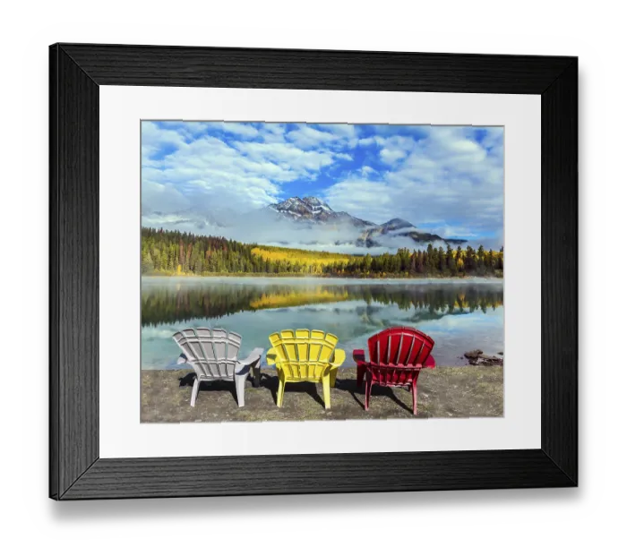 Framed Print : Rocky Mountains of Canada. Three comfortable multi-colored deck chairs stand by the Piramid lake