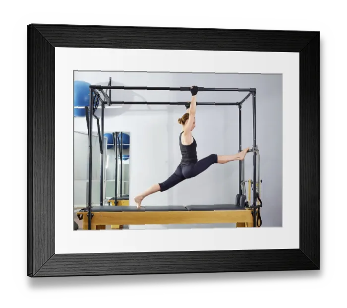 Framed Print : Pilates woman in cadillac legs split reformer exercise at gym