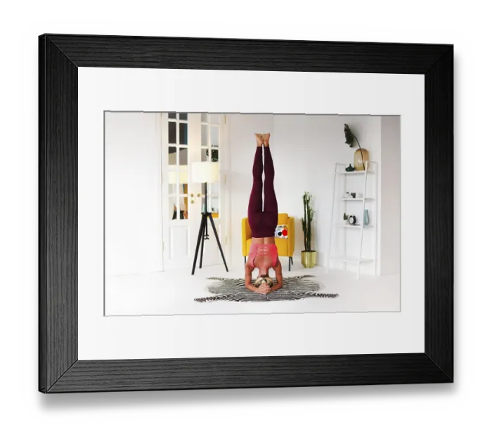 Framed Print : Full body of focused slim female female performing handstand near wall while practicing yoga in light room