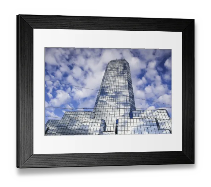 Framed Print : Poland, February 2019: A modern reflective office skyscraper against a blue sky with white clouds Framed Print : Poland, February 2019: A modern reflective office skyscraper against a blue sky with white clouds