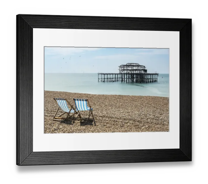 Framed Print : Two folding chairs on the beach in front of the ruins of the burnt down West Pier in Brighton