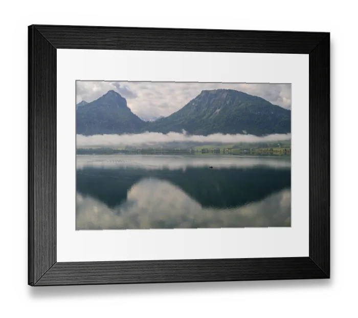 Framed Print : Quiet lake landscape with a small boat and mountains in the background