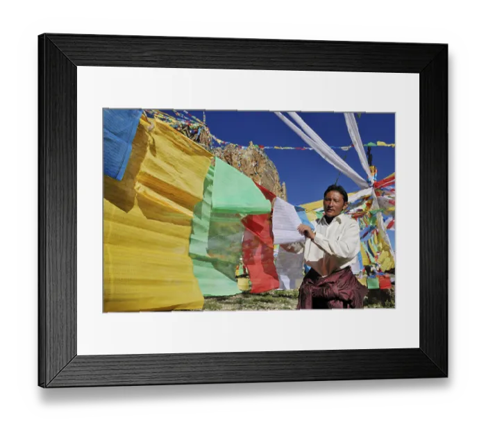 Framed Print : Tibetan pilgrim hanging prayer flags for the upcoming ceremony on Namtso Lake