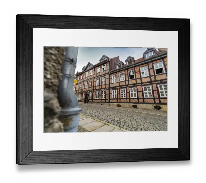 Framed Print : Detailed half-timbered buildings along a cobbled street on a cloudy day Framed Print : Detailed half-timbered buildings along a cobbled street on a cloudy day