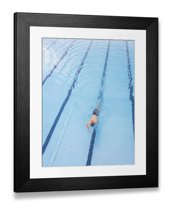 Framed Print : A man swims in the clear blue water of a pool along the lanes